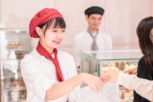 織田製菓専門学校の販売実習でお客様にお菓子を手渡す学生